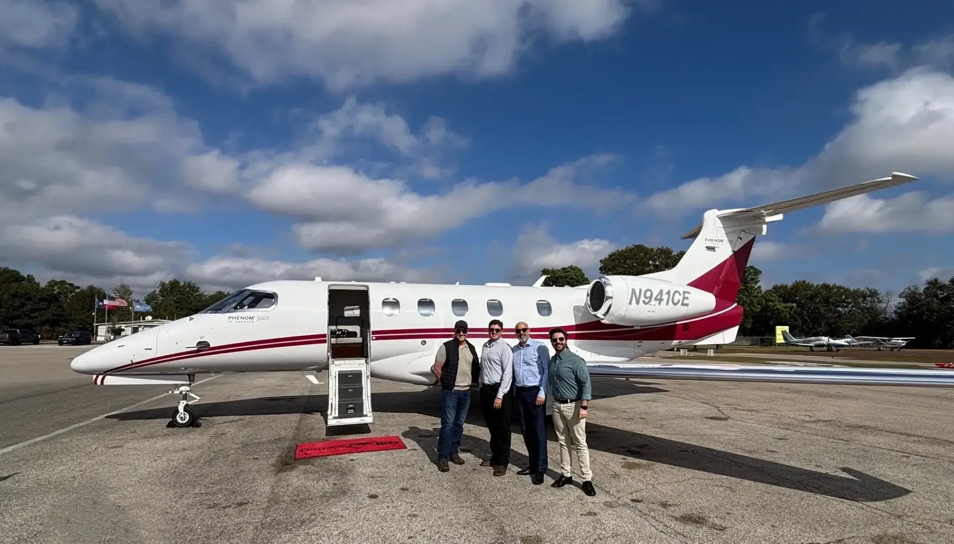 Four people standing by a private jet.