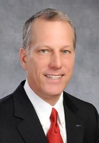 A man in suit and tie smiling for the camera.