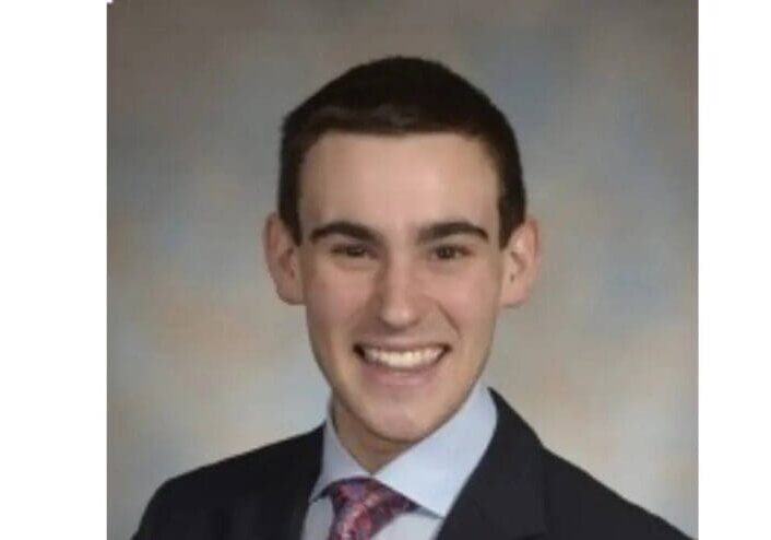 A young man in suit and tie smiling for the camera.