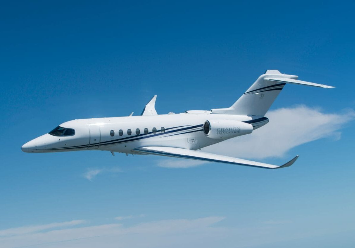 A white jet flying through the air with its landing gear down.