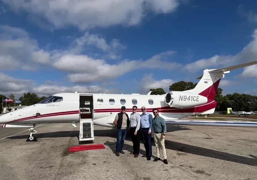 Four people standing by a private jet.