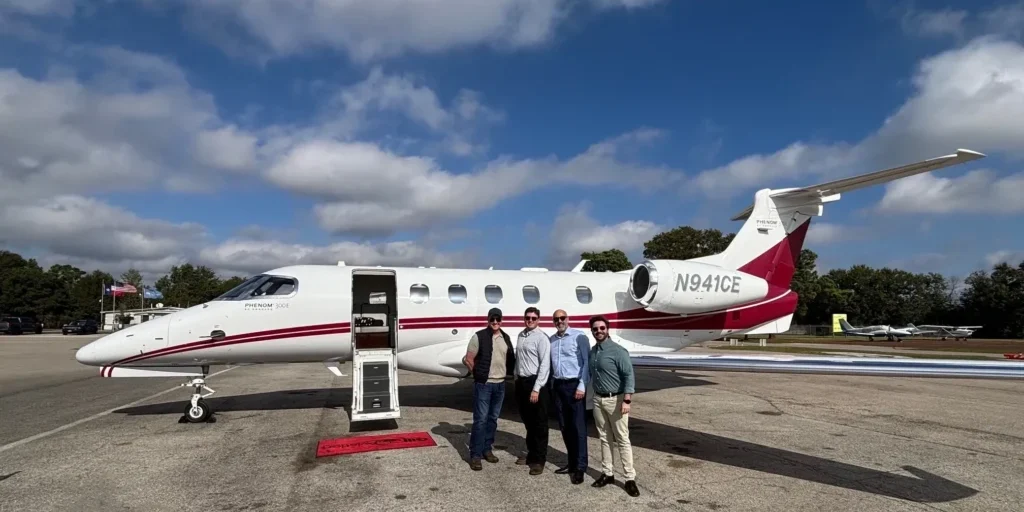 Four people standing by a private jet.