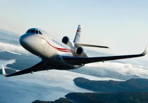 silver private jet with red stripes over islands