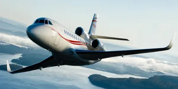 silver private jet with red stripes over islands
